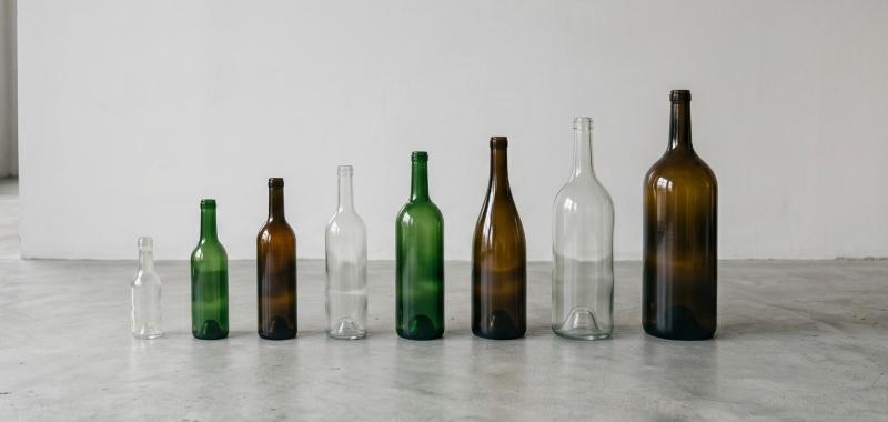 a row of em[ty wine bottles of various sizes on a warehouse floor