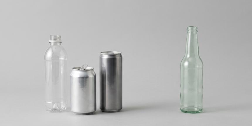 Plastic bottle, aluminium can, and steel can grouped together with a single glass bottle set apart, representing containers in and out of scope of the UK's 2027 Deposit Return Scheme.